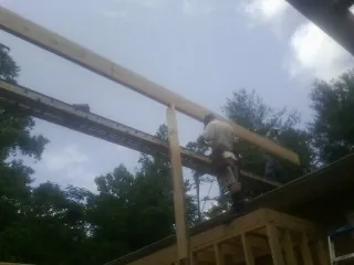 Carpenter setting a ridge beam over a new addition frame — Ice Dam Removal by Roofing Brothers in Irvington