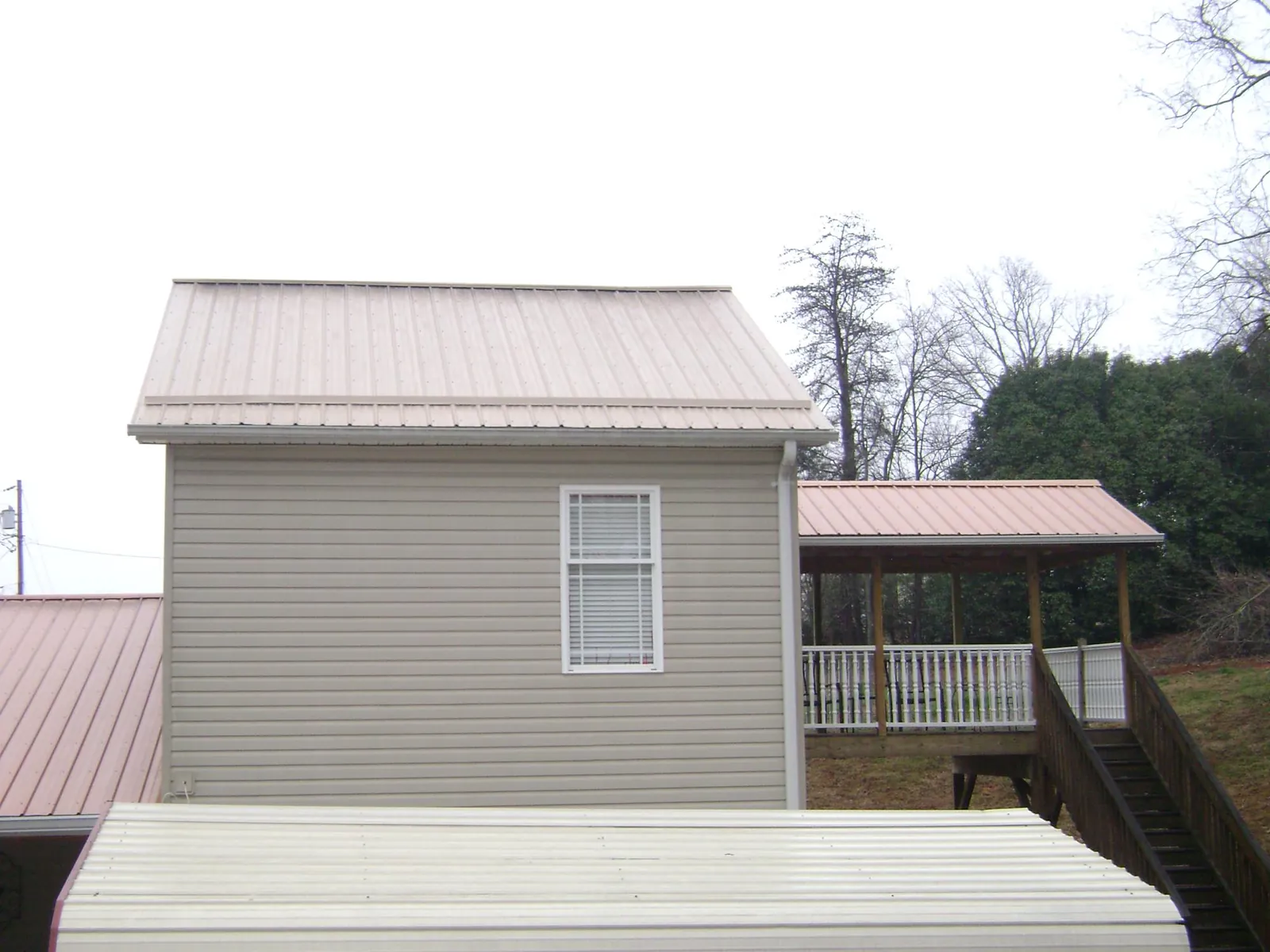 Tan metal roofs on a two story addition and attached porch, from a Roof Replacement job in Irvington