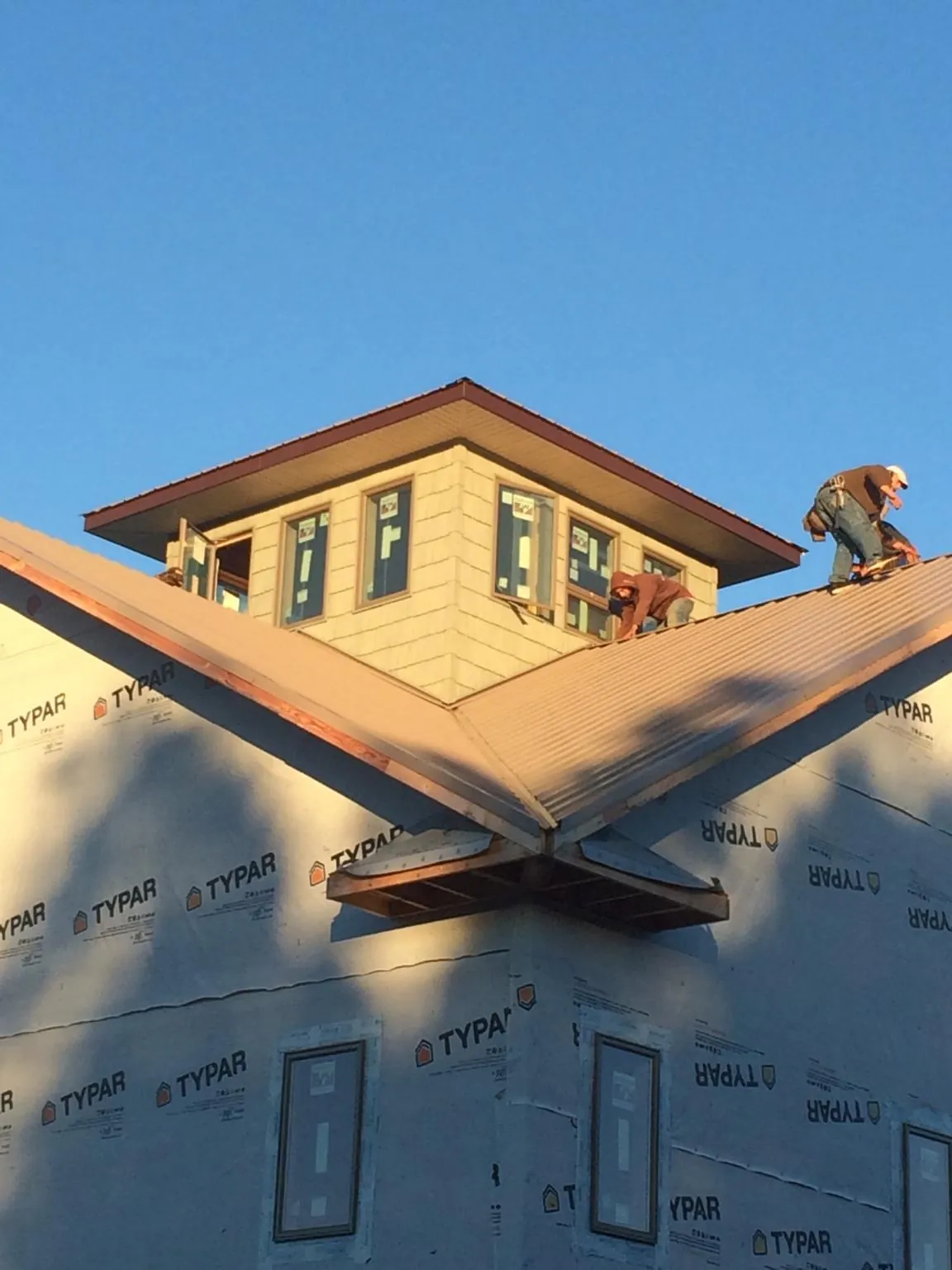 Roofers working around a rooftop cupola on a new metal roof at sunset — Roof Waterproofing in Irvington by Roofing Brothers